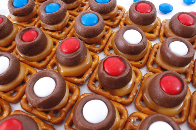 These Patriotic Caramel Pretzel Bites are great 4th of July treats. Sweet, salty, crunchy and delicious they are great Red White and Blue dessert for 4th of July, Memorial Day or even an Olympics viewing party. Pin this fun Fourth of July dessert for later and follow us for more 4th of July Food ideas.