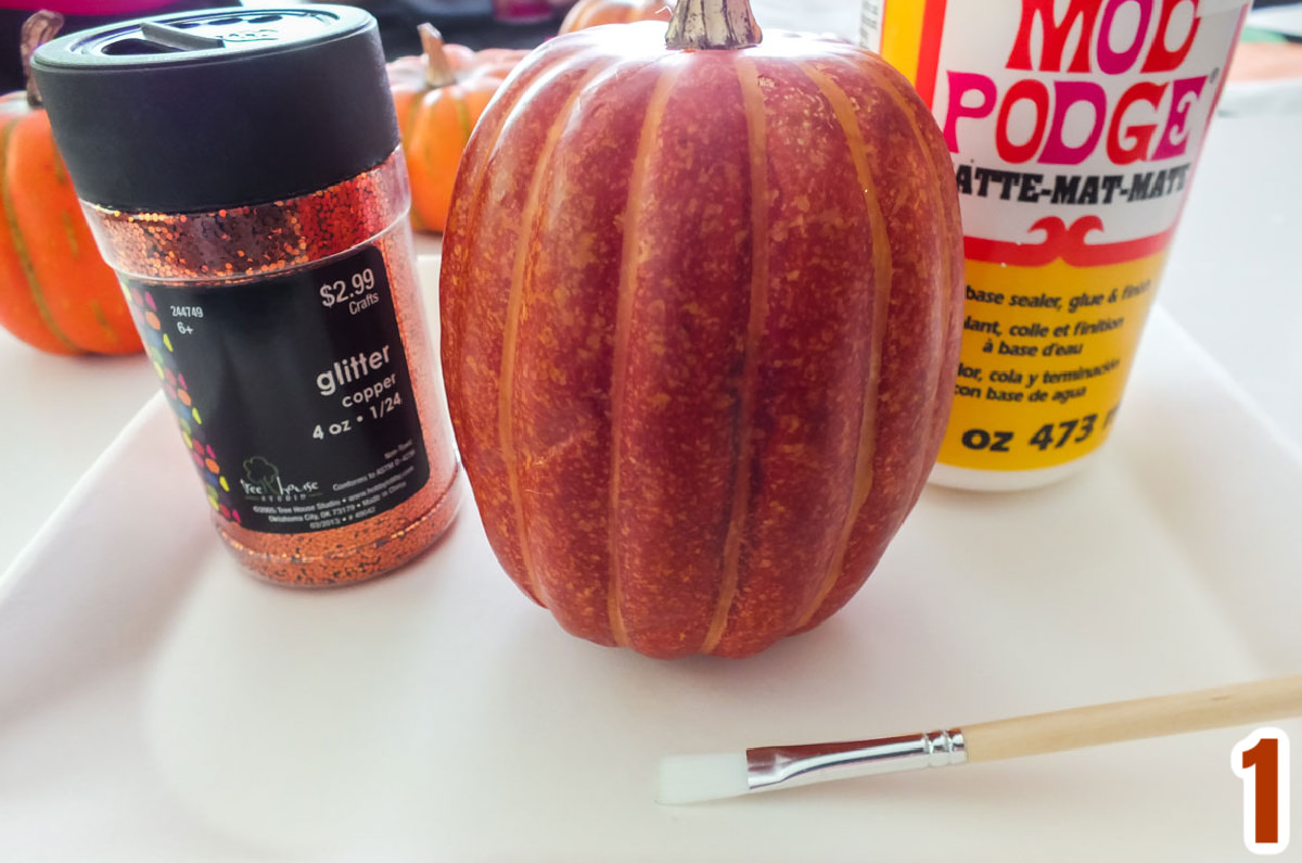 All the supplies you will nee to Make DIY Glitter Pumpkins including faux pumpkins, glitter, Mod Podge and a craft brush.