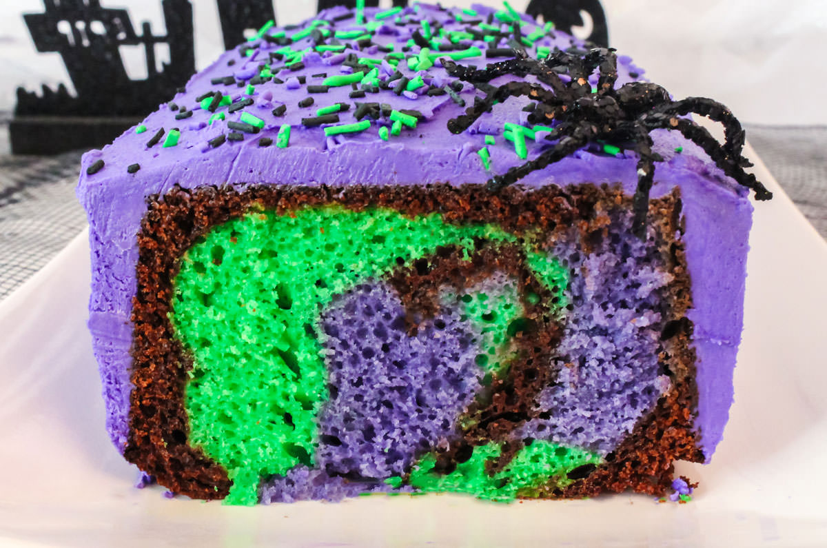 Closeup on a Bewitched Marble Cake that has a sliced removed so you can see the Halloween color marble effect inside the cake.