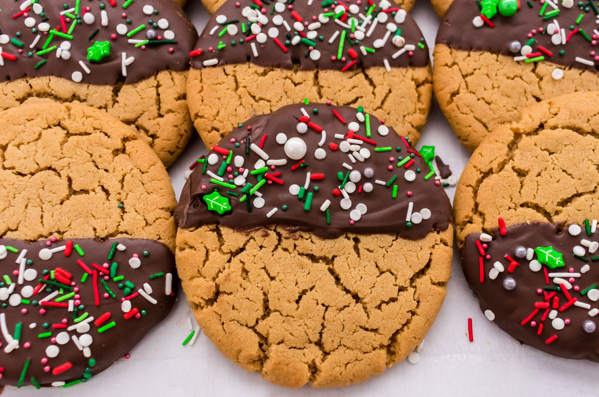 Two rows of Chocolate Dipped Peanut Butter Cookies laying on top of each other on white parchment paper.