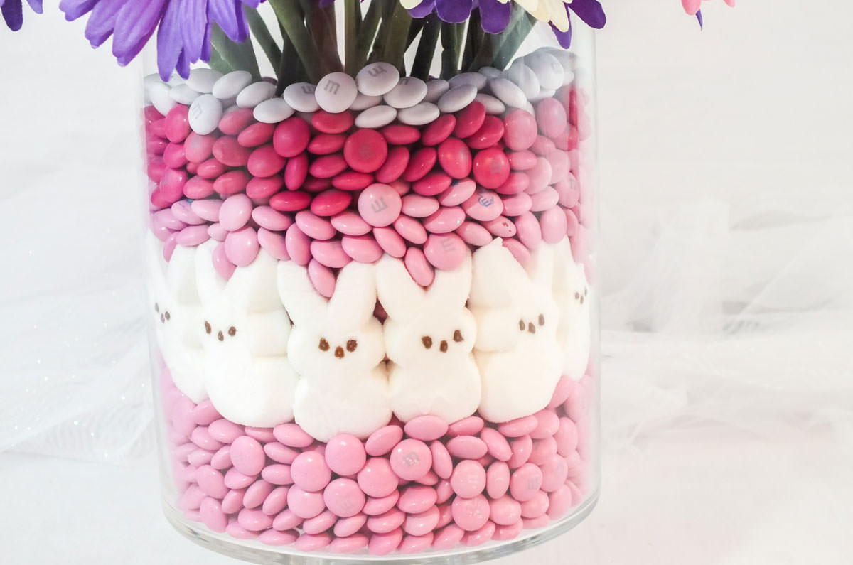 Closeup of the hurricane vase of the Easter Peeps Candy Centerpiece showing the layers of pink and white M&M's and the White Bunny Peeps.