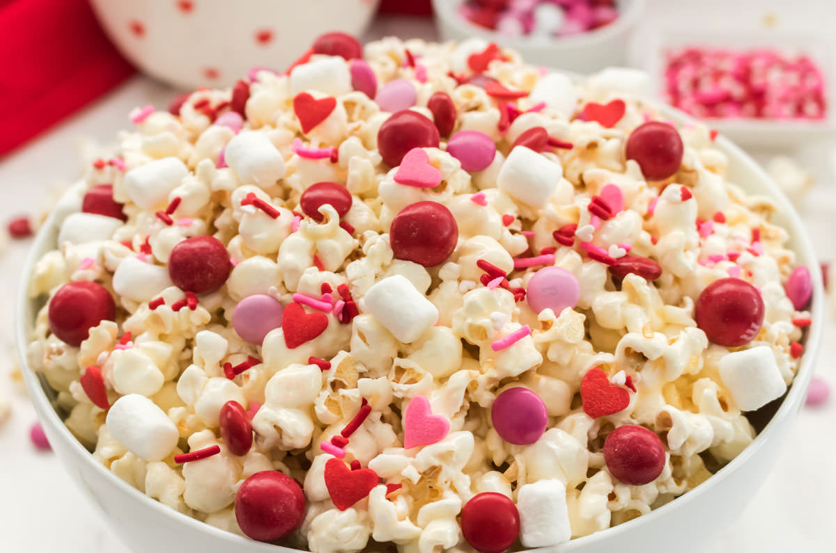 Close up on a white bowl sitting on a white surface filled with Valentine's Day Popcorn.