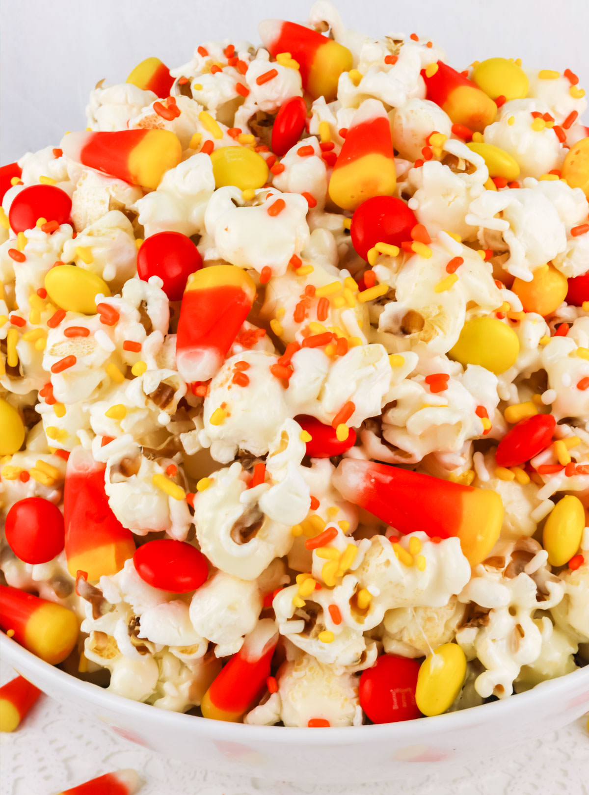 Closeup on a white serving bowl filled with Fall Candy Corn Popcorn.