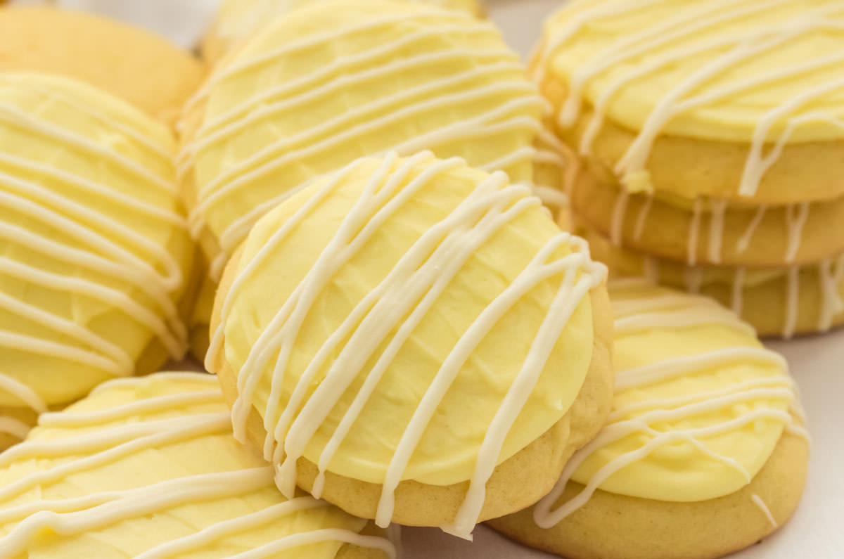 Closeup on a stack of Lemon Cookies with Lemon Frosting laying on a white surface.