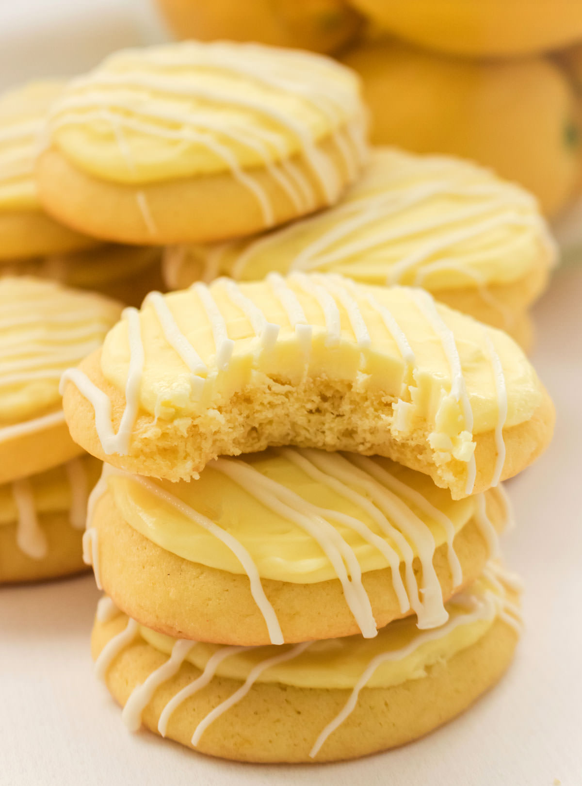 Close up on a stack of Lemon Cookies with Lemon Frosting, the top cookie has a bit taken out of it.