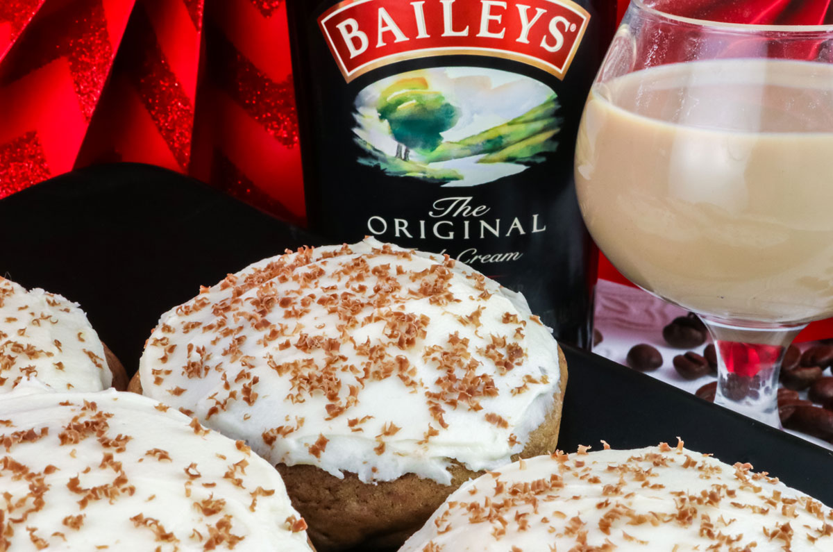 Closeup on a plate filled with Coffee. Cookies with Baileys Irish Cream Frosting sitting next to a glass of Baileys.