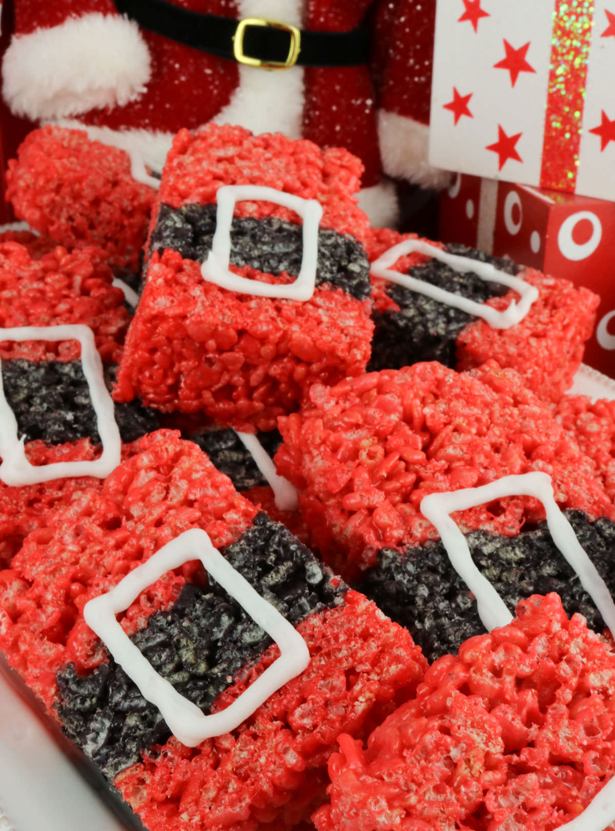 Closeup on a white platter filled with Santa Claus Rice Krispie Treats sitting in front of Christmas decorations.