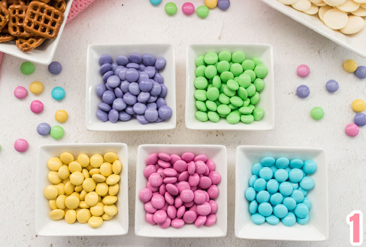  Una bolsa de MM de Mezcla de Pascua separados por color, cada color en su propio ramekin blanco.